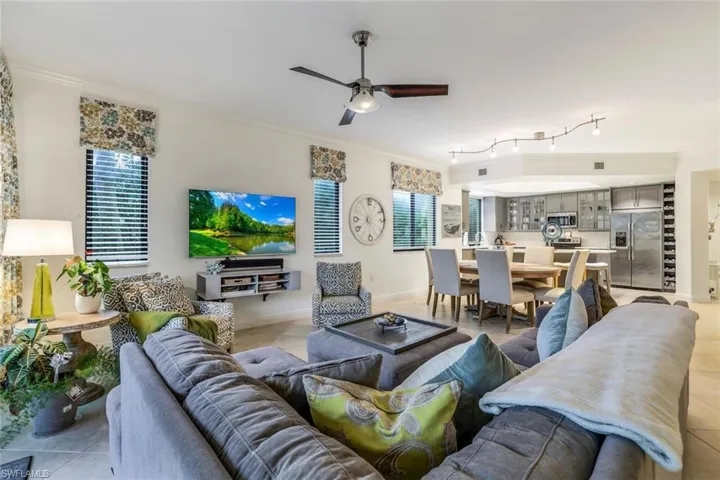 Living room featuring crown molding, light tile patterned flooring, and ceiling fan