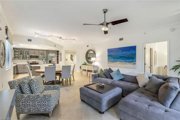 Living room featuring ceiling fan, ornamental molding, and light tile patterned flooring