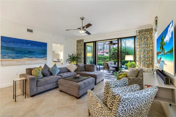 Living room with ceiling fan, crown molding, and light tile patterned flooring
