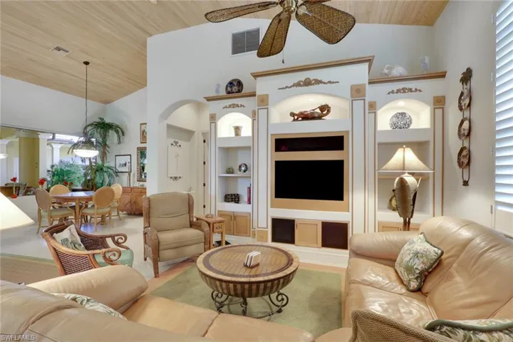 Living room with wood ceiling, built in shelves, high vaulted ceiling, and a ceiling fan