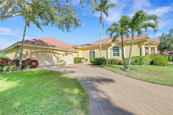 View of front of property featuring a front lawn, stucco siding, decorative driveway, an attached garage, and a tiled roof
