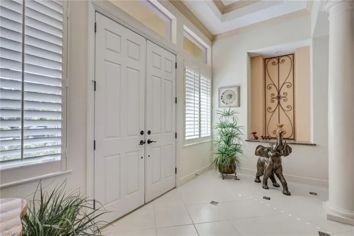 Tiled foyer featuring ornate columns and ornamental molding