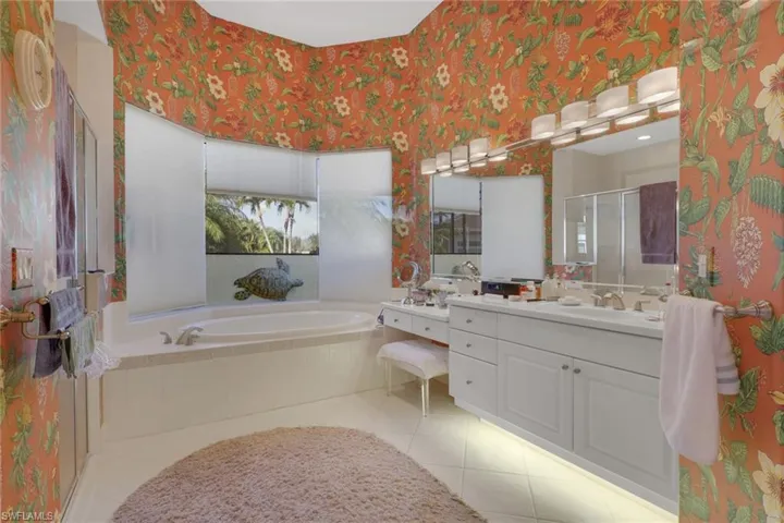Bathroom with a stall shower, a garden tub, wallpapered walls, vanity, and light tile patterned flooring
