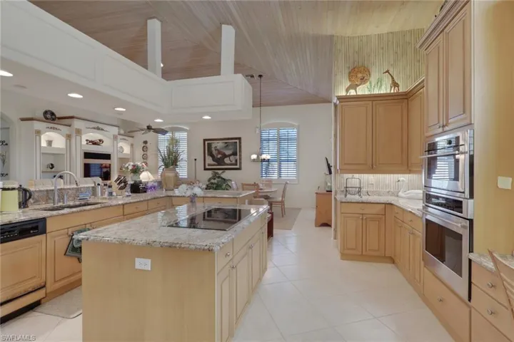 Kitchen featuring light brown cabinets, dishwasher, light stone counters, stainless steel double oven, and wood ceiling