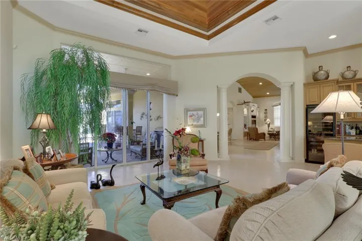 Living room with decorative columns, crown molding, and arched walkways