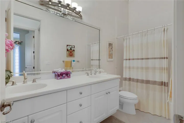 Bathroom featuring double vanity, shower / bath combo, and light tile patterned floors