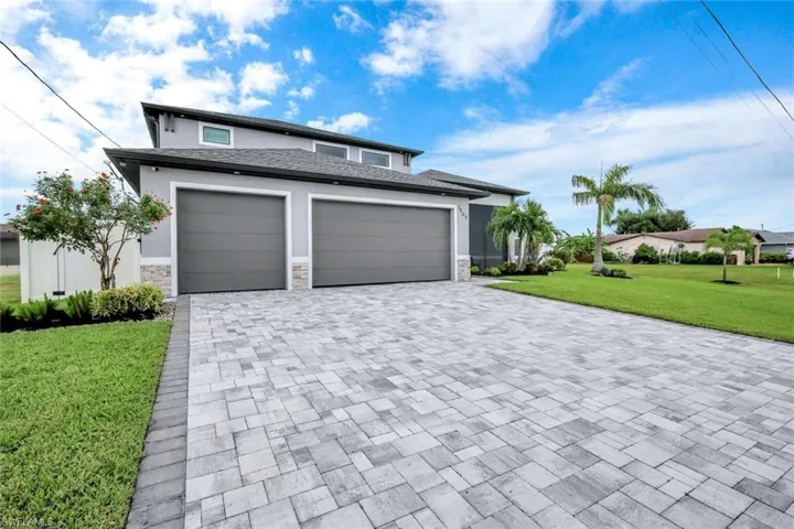 View of front of property with a front lawn, stone siding, stucco siding, and decorative driveway