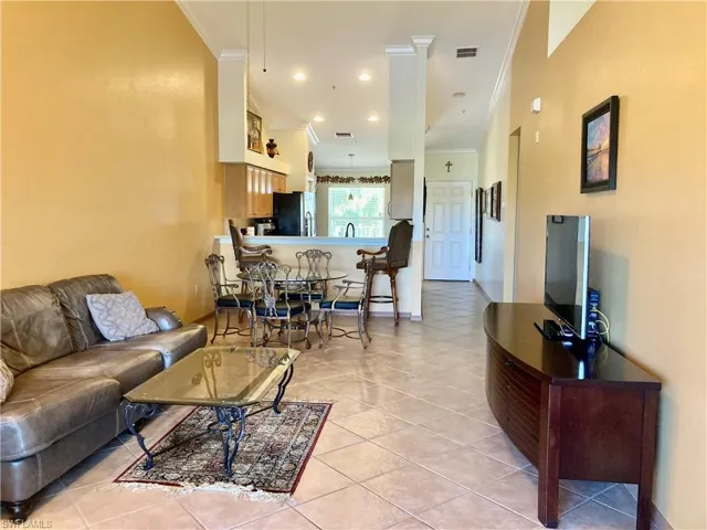 Living room featuring ornamental molding, light tile patterned floors, and recessed lighting