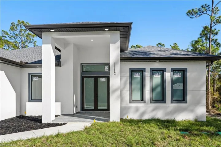 Property entrance featuring stucco siding and roof with shingles