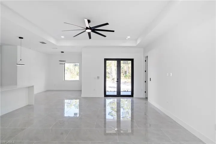 Empty room with french doors, a raised ceiling, a ceiling fan, and recessed lighting
