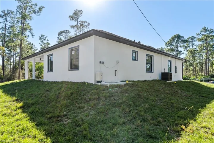 Rear view of property with stucco siding and a yard