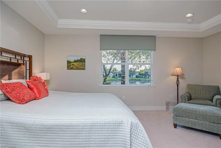 Bedroom featuring a tray ceiling, ornamental molding, and light colored carpet