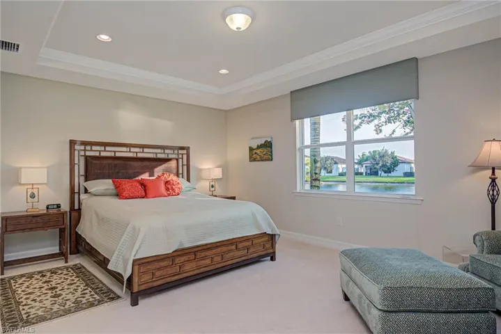 Bedroom with ornamental molding, a tray ceiling, and carpet