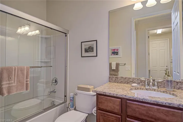 Full bathroom with toilet, vanity, and shower / bath combination with glass door