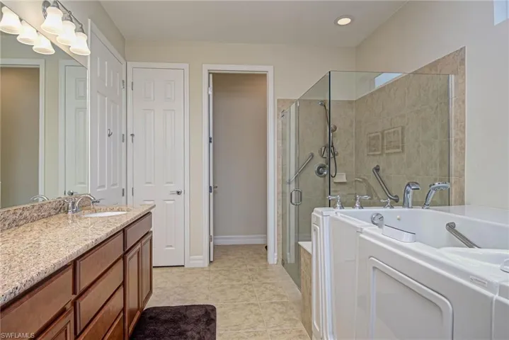 Bathroom featuring shower with separate bathtub, vanity, and tile patterned floors