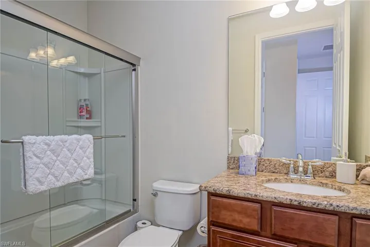 Full bathroom featuring enclosed tub / shower combo, vanity, and toilet
