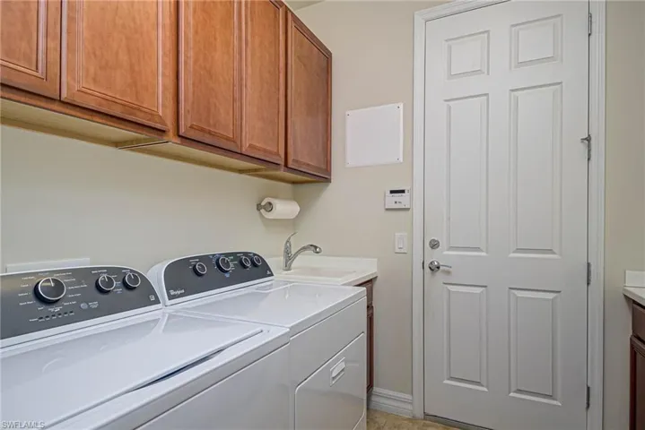 Clothes washing area featuring cabinets, independent washer and dryer, light tile patterned flooring, and sink