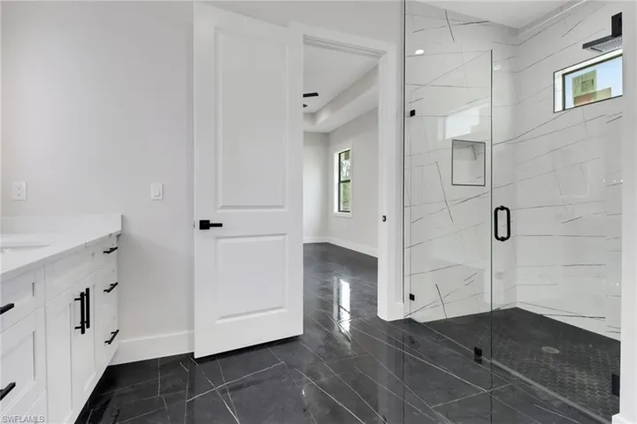 Primary Bathroom featuring vanity, tile flooring and upgraded shower with frameless glassdoor