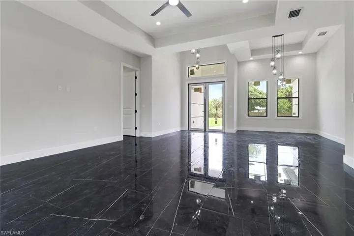 Great room featuring a tray ceiling with ceiling fan, modern light fixtures and tile flooring