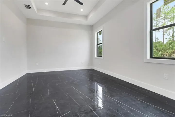 Primary bedroom featuring tile flooring, tray ceiling, recessed lighting and a ceiling fan