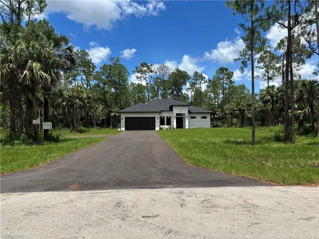 View of front of house featuring an attached garage, driveway, and a front lawn