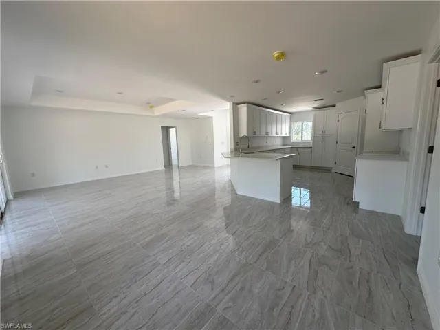 Unfurnished living room a tray ceiling, and light tile floors