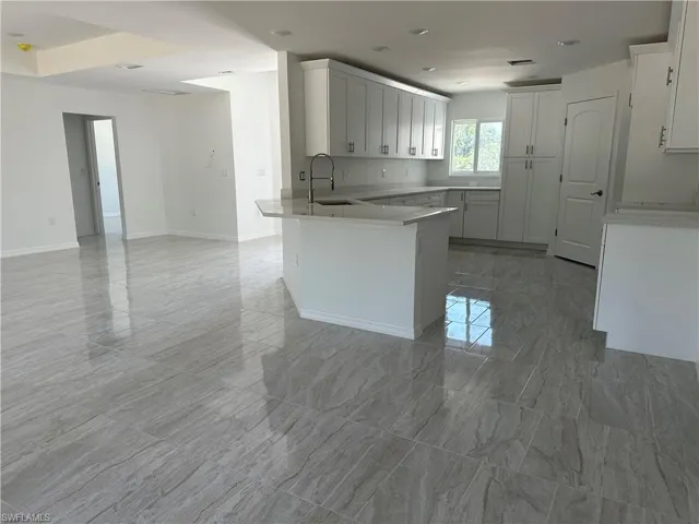 Kitchen featuring white cabinetry, sink, kitchen peninsula, and light tile floors