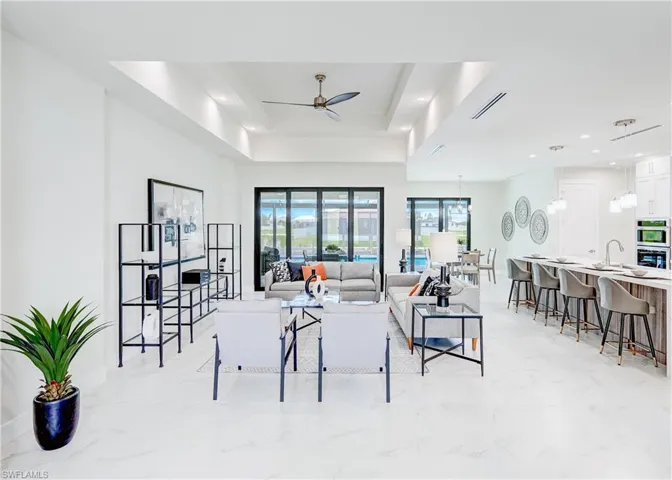 Tiled living room featuring ceiling fan, sink, and a tray ceiling