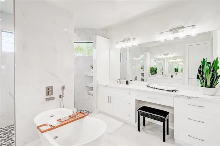 Bathroom featuring tile patterned floors, a washtub, tile walls up to the ceiling, and double vanity.
