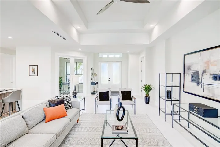 Tiled living room featuring french doors, ceiling fan, and a raised ceiling