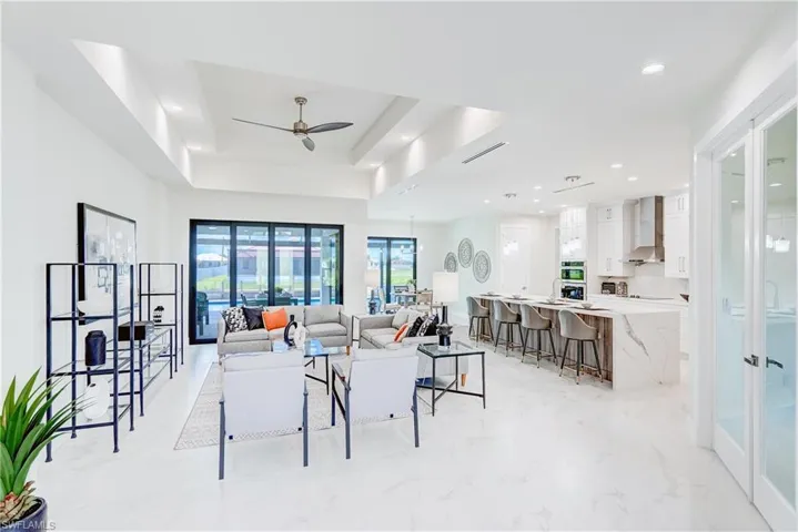 Dining space featuring light tile patterned flooring, ceiling fan, and a tray ceiling