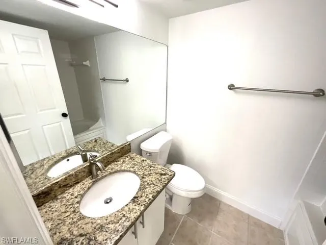 Full bathroom featuring toilet, vanity, tile patterned floors, and tub / shower combination