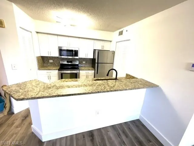 Kitchen featuring kitchen peninsula, white cabinetry, and stainless steel appliances