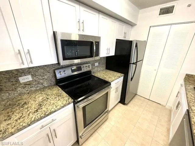 Kitchen featuring white cabinetry, dark stone countertops, and appliances with stainless steel finishes