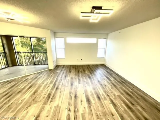 Unfurnished room with a textured ceiling and hardwood / wood-style flooring