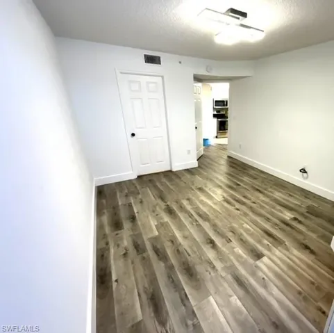 Unfurnished room featuring dark wood-type flooring and a textured ceiling