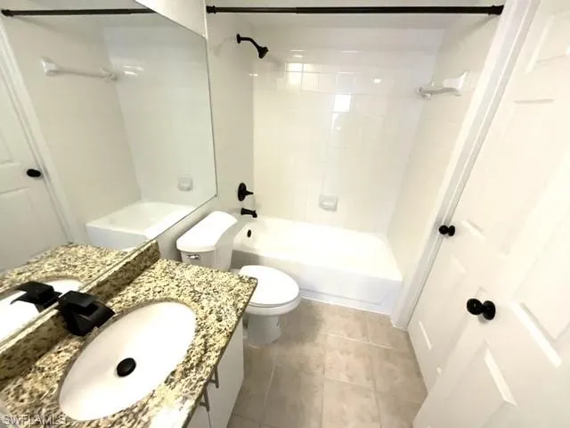 Full bathroom featuring toilet, tiled shower / bath combo, vanity, and tile patterned floors