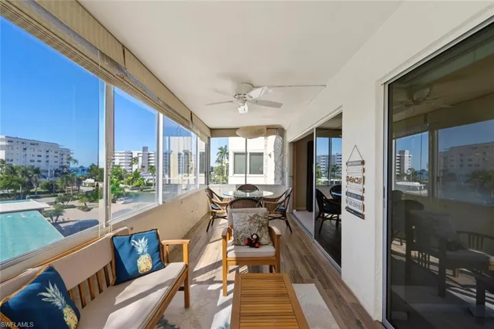 Sunroom with wood finished floors, ceiling fan, and a view of city