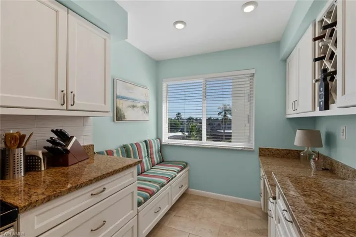 Kitchen featuring dark stone countertops, white cabinetry, light tile patterned floors, and recessed lighting
