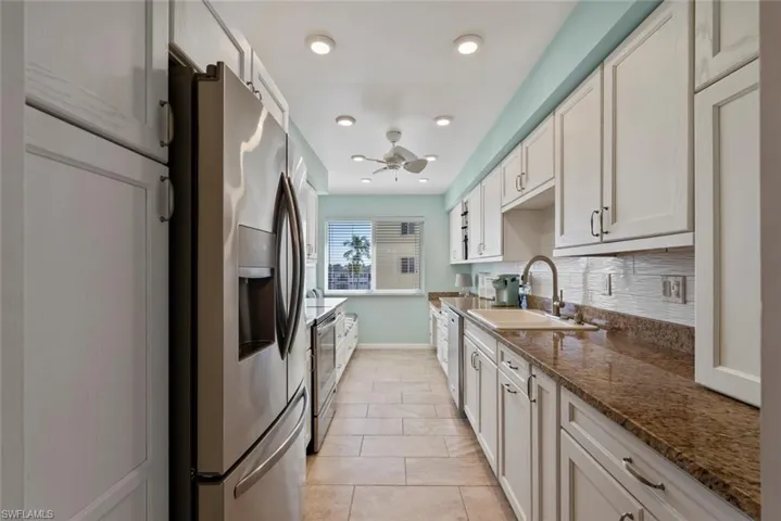Kitchen with stainless steel appliances, tasteful backsplash, white cabinets, and recessed lighting