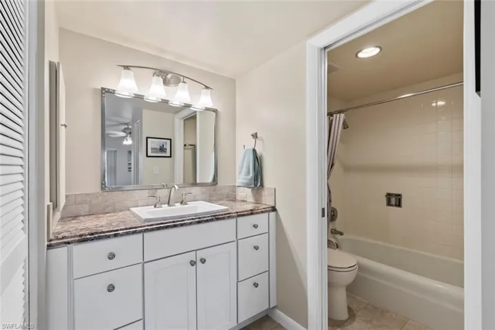 Bathroom featuring vanity, shower / tub combo with curtain, light tile patterned flooring, and recessed lighting