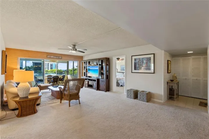 Living area featuring light carpet, ceiling fan, a textured ceiling, and a sunroom