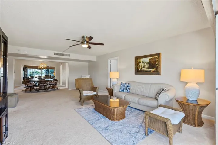 Carpeted living room with a ceiling fan and a chandelier