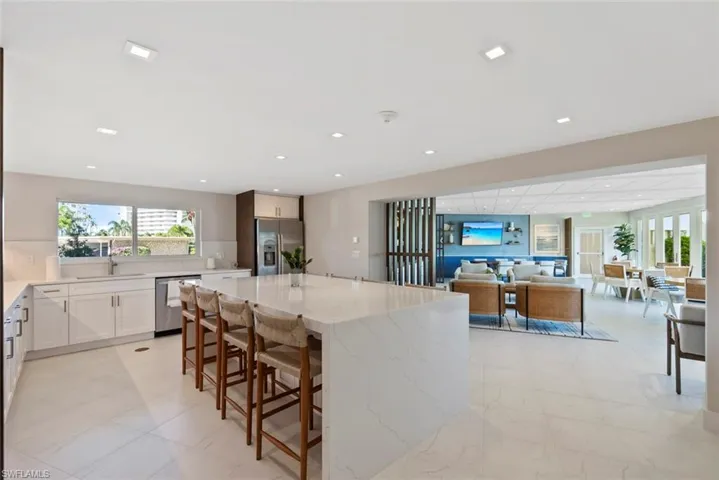 Kitchen with light stone counters, appliances with stainless steel finishes, white cabinetry, a center island, and recessed lighting