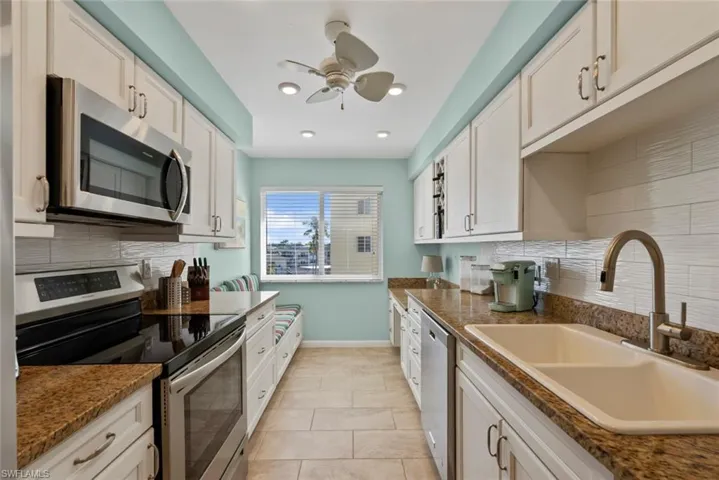 Kitchen with tasteful backsplash, stainless steel appliances, white cabinetry, and recessed lighting