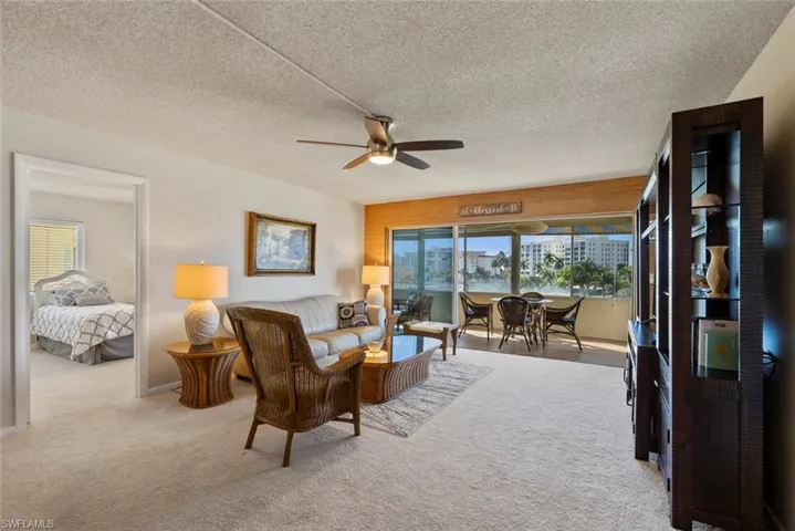 Living area with light colored carpet, a textured ceiling, and ceiling fan