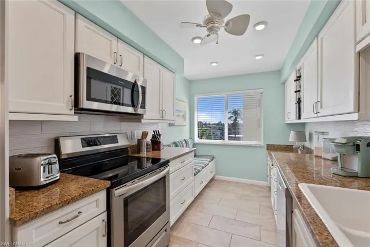 Kitchen featuring backsplash, stainless steel appliances, white cabinetry, light tile patterned floors, and recessed lighting