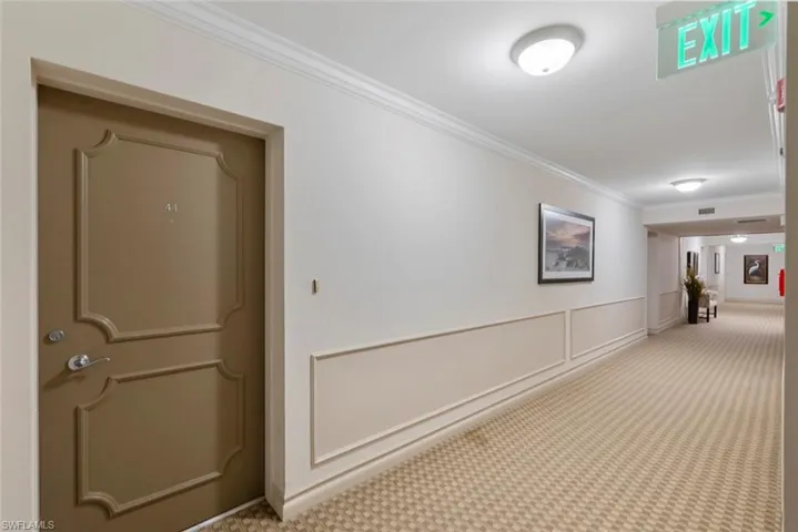 Hallway featuring crown molding, carpet flooring, and a decorative wall