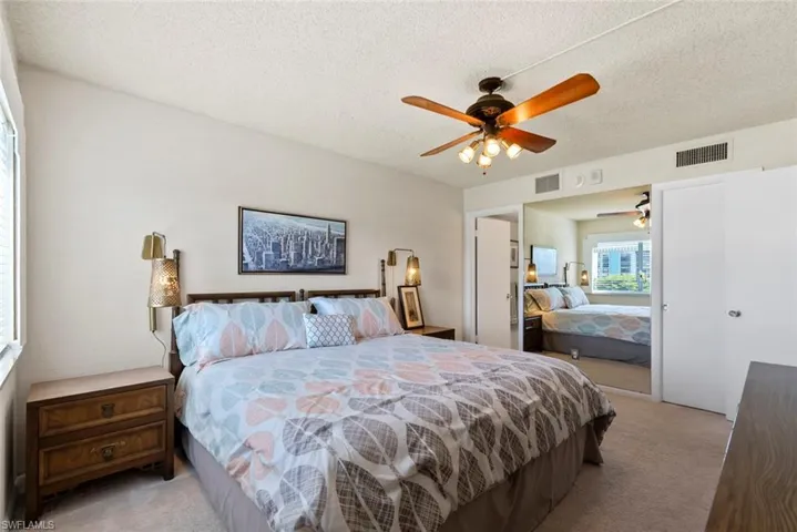 Bedroom with light carpet, a textured ceiling, a ceiling fan, and a closet