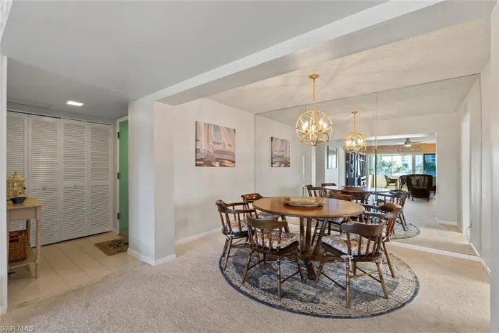 Dining area with light carpet, a chandelier, light tile patterned floors, and a ceiling fan